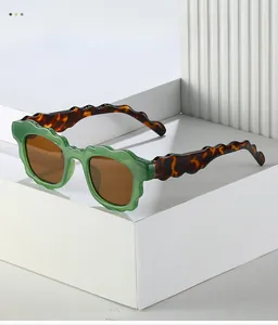Detail of green wavy frame sunglasses with tortoiseshell temples on geometric stand