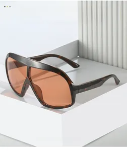 Détail de lunettes de soleil écaille avec verres orange sur un support géométrique