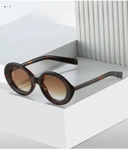 Detail of round tortoiseshell sunglasses with gradient lenses on a white display stand