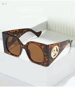 Détail de lunettes de soleil carrées écaillées avec logo doré sur support blanc