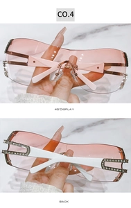 Detail of pink rimless sunglasses with rhinestone accents and white temples on marble