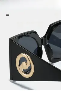 Détails de lunettes de soleil carrées noires avec garniture métallique dorée sur la branche