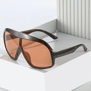 Lunettes de soleil oversize écaille de tortue avec verres orange sur socle blanc épuré