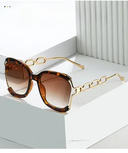 Détail de lunettes de soleil écaille avec branches chaîne dorées sur socles