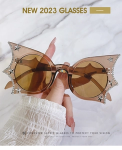 Detail of bat-wing butterfly sunglasses with rhinestones and silver stars over marble background