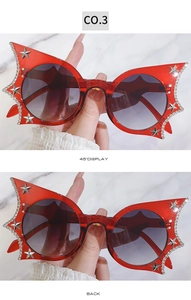 Close-up of red cat-eye sunglasses with gradient purple lenses and rhinestone star details
