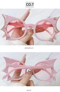 Detail view of pink bat-shaped sunglasses with rhinestones and star accents