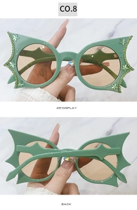 Detail view of green batwing sunglasses with rhinestones and star accents, 45-degree angle