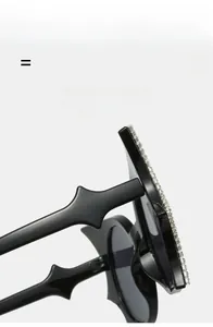 Macro shot of black designer sunglasses with rhinestone trim and wavy temple detail