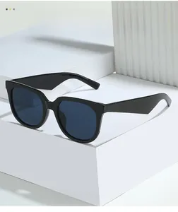 Detail of oversized black frame sunglasses with deep blue lenses on a white display block