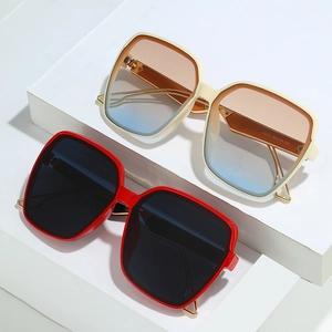 Stylish square oversized sunglasses with red and ivory frames on geometric white stand