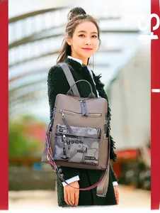 Close-up of taupe backpack with colorful woven strap and graffiti detail on a street