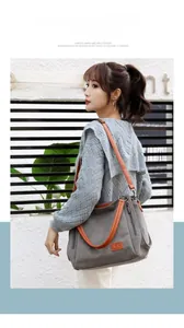 Detail of grey canvas tote with brown leather handles and side zipper pocket