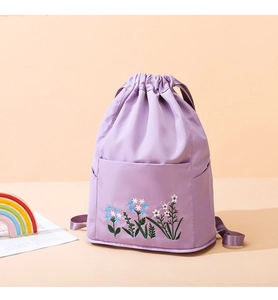 Detail of lavender drawstring backpack featuring blue and white floral embroidery and pockets