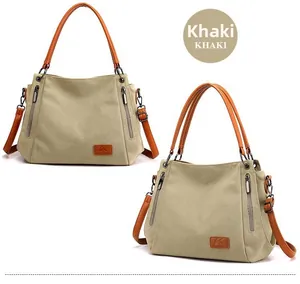 Detail view of khaki canvas tote bag featuring brown leather straps and metallic side zipper