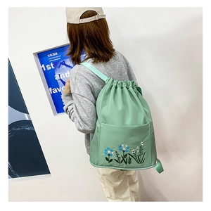 Detail of light green oxford backpack with blue floral embroidery and drawstring closure