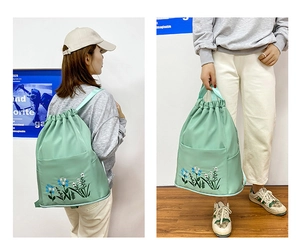 Detail of mint green waterproof nylon backpack with floral embroidery and drawstring closure