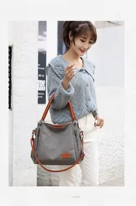 Detail of grey canvas tote bag with leather handles and decorative side zippers