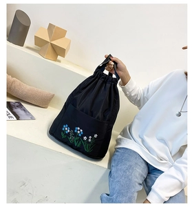 Close-up of black nylon bucket bag featuring delicate floral embroidery and drawstring