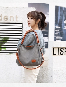 Detail of grey canvas tote with leather straps and functional side zipper pockets