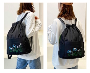 Detail of floral embroidery on a black nylon drawstring backpack for travel and training