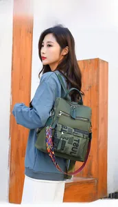 Army green nylon backpack detail showing multiple zip pockets and ethnic woven strap