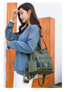 Detail of olive green oxford backpack featuring vintage newspaper print pocket and woven strap