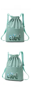 Close-up of mint green nylon drawstring backpack with floral embroidery and side pockets