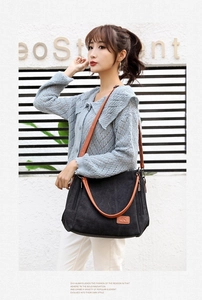 Detail of black canvas tote with brown leather handles and side zipper pocket