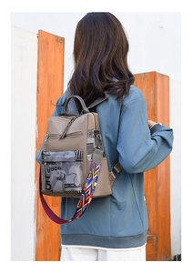 Detail of khaki oxford backpack showing graffiti print and colorful woven shoulder strap