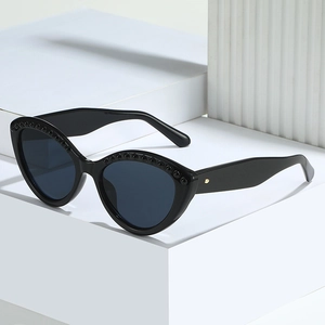 Fashionable black cat eye sunglasses with rivet studs on a white geometric display
