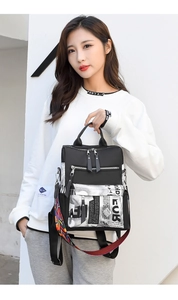 Close-up of black nylon backpack featuring newspaper print panels and colorful woven straps