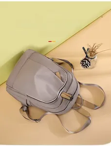 Detail view of khaki Oxford cloth backpack featuring multi-layer zippers and side pockets