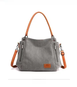 Close-up of gray canvas tote bag featuring dual front zipper pockets and leather handles