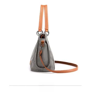 Side view of grey canvas tote bag with brown PU leather handles and metal rings