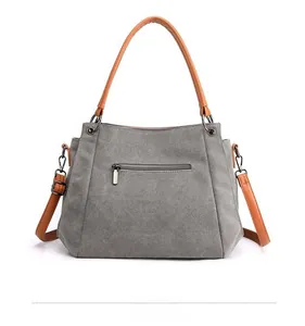 Rear view of canvas shoulder bag showing back zipper pocket and brown faux leather handles