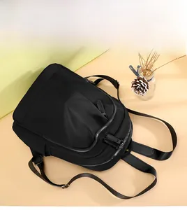 Detail view of the black nylon backpack's minimalist front zipper pocket and fabric texture