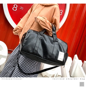 Detailed close-up of large black PU leather travel bag with adjustable strap and dual handles
