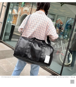 Detailed view of the black PU leather travel bag with adjustable shoulder strap and handle