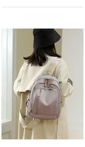 Rear view of a model wearing the purple nylon backpack over a beige trench coat