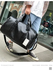 Man holding a black leather travel bag with a shoe compartment in a city street view