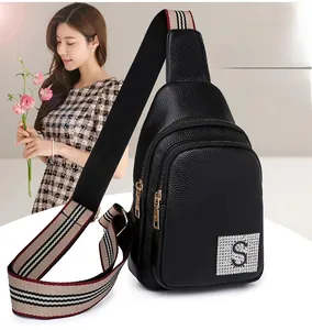 Close-up of black pebble leather chest bag with striped strap and crystal S logo