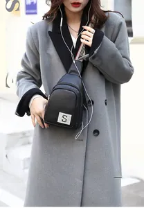 Detail of black pebbled PU leather chest bag with dual zippers and plaid shoulder strap