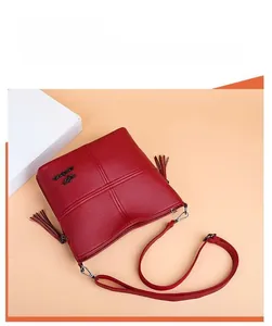 Detail of red quilted PU leather crossbody bag with tassels and adjustable shoulder strap