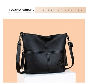 Detail of black pebbled leather crossbody bag with fringe tassel and metallic logo