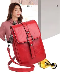 Detail of red pebbled PU leather crossbody bag with metal buckle and side zipper pocket