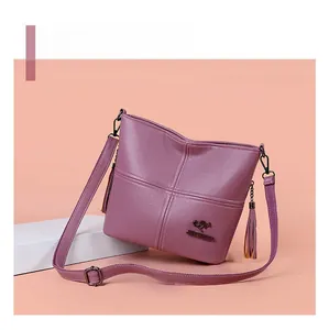 Detail of purple textured PU leather handbag with fringe tassel and metallic logo