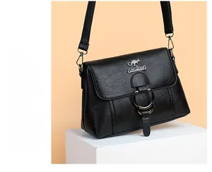 Detail of black pebbled leather handbag with gold kangaroo logo and magnetic flap closure