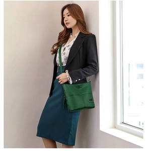 Detailed view of dark green pebbled leather shoulder bag with cross-stitch pattern