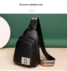 Detail of black pebbled PU leather chest bag with crystal S patch and striped fabric strap